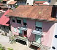 Two story pink house, red roof, multiple balconies