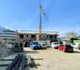 construction site with a crane, white vans, scattered construction materials, distant buildings, mountainous background