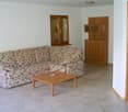 floral print couch, wooden table, wall mounted lamp, cupboard, window