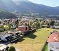 Open grass field, mountain view, multiple houses in a row, brick houses, trees