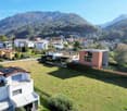 House with solar panels on the roof, large grassy field in front, elevated terrain with a wide view of the mountains.