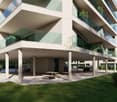 Modern apartment building with glass balconies, underground parking, and a green lawn