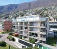 Modern apartment building with multiple balconies, swimming pool, and a view of the mountains