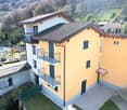 3 story house, yellow exterior, brown roof, balconies, multiple windows, tiled courtyard