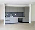 modern kitchen with gray cabinets, black countertops, stainless steel sink, built-in oven, tiled floor