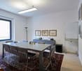Meeting room with desk, chairs, carpet, wall paintings, TV, lamp, whiteboard, storage cabinet, microwave
