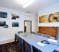 Long desk, 6 chairs, rug, wood bench, paintings, monitor, mouse, papers, mirror