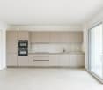 modern minimalist kitchen with built-in oven and sink, sliding door to balcony