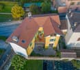 2 story house, yellow exterior, brown roof, balcony, central courtyard, surrounded by trees
