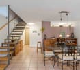 wooden floor, glass table, modern chairs, bar stool, wooden shelves, dining room lamps, staircase
