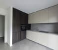 Modern kitchen with white and dark wood cabinets, built-in oven, and a sink with a faucet. The countertop appears to be made of a gray material, possibly concrete or stone. The floor is covered with a light-colored tile or laminate flooring.