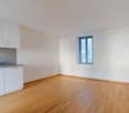 room, hardwood floors, white walls, window, kitchen area with sink and cabinets