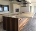 Kitchen: Central island with a large countertop, wooden base, integrated oven, hood, modern appliances, neutral colors, ample space, natural light