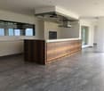 Open kitchen with white cabinets, wooden countertop, island, modern appliances, tiled floor