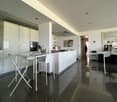 modern kitchen, white cupboards, island with a dining table, white table and chairs, oven and dishwasher built-in, white flooring, white ceiling