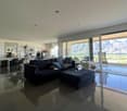 modern living room with large windows and sliding doors leading to balcony, large sofa, coffee table, and modern floor lamp