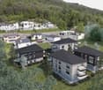 5 buildings in residential area, black rooftops, several windows, solar panels on some houses, surrounded by trees and grass