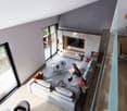 Spacious living room with large windows, grey sofa, coffee table, TV stand, and a child playing with stuffed animals