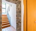 Wooden staircase with metal railing, stone walls, and a fireplace visible in the background