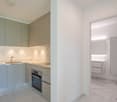 Modern kitchen with light gray cabinets, white marble countertops, built-in oven, and dishwasher