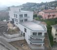 White modern building with a raised ground floor, terraces, and a swimming pool