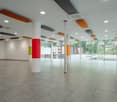 Large open space with white ceiling, colorful columns, gray tiles, large windows, glass doors