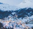 Snowy mountainous landscape with a village, numerous buildings and a mountain in the background