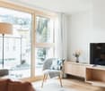 double sofa, wooden chair, desk with TV, large glass windows, floor lamp, floor with carpet