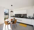 modern kitchen, white cabinets, black countertops, stainless steel appliances, dining table, chairs