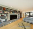 Living room with a large bookshelf, a flat screen TV, a gray couch, a glass table, and a glass door leading to a balcony.