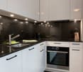 Modern kitchen with white cabinets, black countertops, built-in oven, and dishwasher