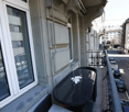 Balcony with black table and chairs, overlooking a city street with buildings and cars