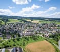 Townscape with houses, trees, and open green fields; a mix of houses and residential areas, surrounded by lush greenery and farmland.