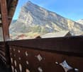 Rustic balcony with wooden railings and mountain view.