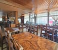 wooden chairs and tables, wooden ceiling, tiles, large windows, counter with shelves, coffee machine