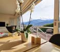 A table with a flower vase, a wooden chair, a side table, and a TV