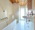 Bathroom with bathtub, toilet, sink, wooden ceiling, white tiles, shower head