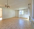Empty room with white walls, tiled floor, two chandeliers, window with white curtains, radiator
