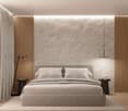 Spacious bedroom with a minimalist design, featuring a large bed with white bedding, wooden side tables, and a textured concrete wall. The room is illuminated by a pendant light fixture and a floor lamp, creating a cozy and relaxing atmosphere.
