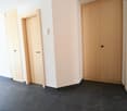 Empty hallway with tiled floors, two wooden doors, light on the ceiling.