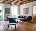 wooden floor, sofa, coffee table, armchair, plant, two paintings, wooden ceiling