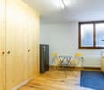 wooden cabinets, wooden floor, tall cabinets, refrigerator, yellow chairs, round table, radiator, window, coffee machine