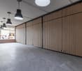 Empty room with gray tiled floor, wooden wall panels, and hanging lamps