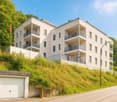Modern building with white facade, multiple balconies, underground garage, and set on a hill.