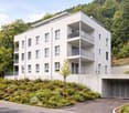 White house, 3 floors, multiple balconies, underground garage, green landscape