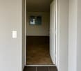 An empty corridor with dark brown floor, light white walls, and a switch in the wall.