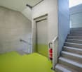 stairs and elevator entrance, yellow floor, concrete walls, fire extinguisher, windows