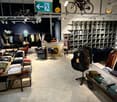 clothes on racks, wooden tables, shelves with clothes, hanging bicycles, bright lights