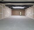 Empty room with concrete floor, unfinished walls, metal beams, glass door, skylight
