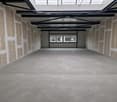 Empty room with concrete floor, unfinished walls, metal beams, windows